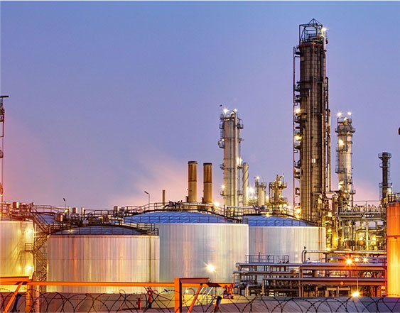 A group of large oil tanks in front of some towers.